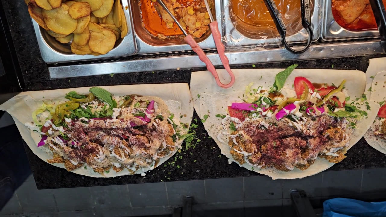 Zwei frisch belegte Falafel-Wraps mit Tahini, Kräutern und eingelegtem Gemüse an der Theke von FALFOOL